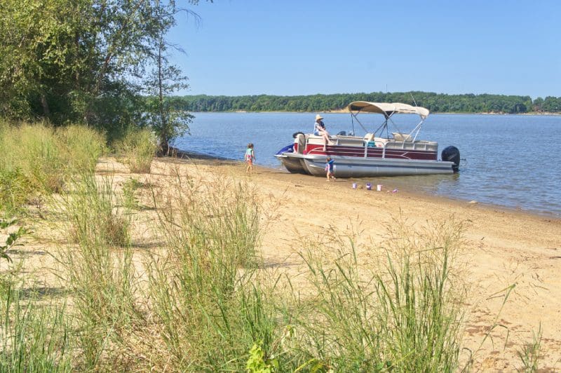 A boat is parked on the shore of a lake.